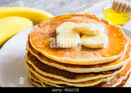 Deliziose frittelle di banane e miele su tavola in legno rustico. close up Foto Stock