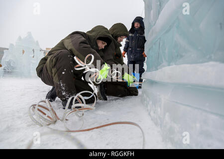 Elettricisti il montaggio di un cavo di alimentazione per illuminare le figure di ghiaccio. Foto Stock