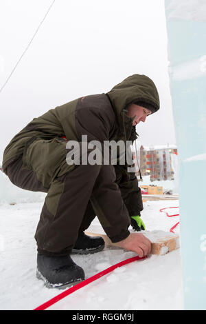 Elettricista si monta il cavo di alimentazione per illuminare le figure di ghiaccio. Foto Stock