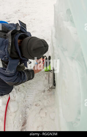 Elettricista monta torcia LED per illuminare la figura di ghiaccio Foto Stock