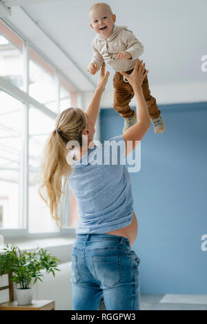 Madre Pegnant sollevamento felice figlio toddler Foto Stock