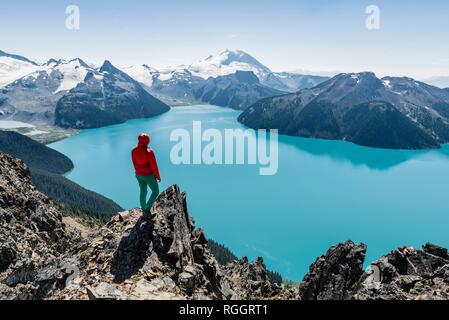 Vista dal crinale panoramico sentiero escursionistico, Escursionista su una roccia, Garibaldi lago, montagna di guardia e inganno di picco, ghiacciaio indietro Foto Stock