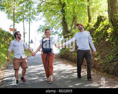 Genitori felici con baby girl passeggiando mano nella mano con un amico Foto Stock