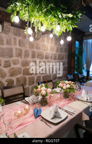 Tabella set e decorate con fiori per una cena nuziale sotto illuminazione artificiale Foto Stock