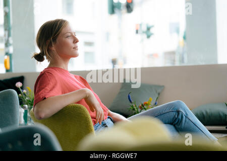 Giovane donna seduta in un caffè Foto Stock