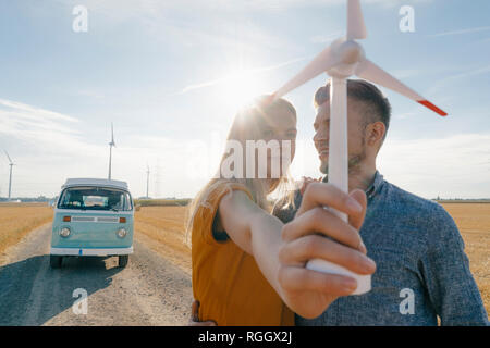 Coppia giovane a camper van nel paesaggio rurale azienda vento modello di turbina Foto Stock