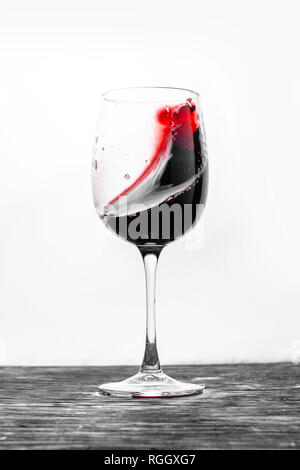 Il vino rosso in vetro schizzi in azione su uno sfondo bianco. Design elegante card Foto Stock