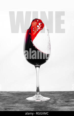 Il vino rosso in vetro schizzi in movimento su uno sfondo bianco. Design elegante card con testo Foto Stock