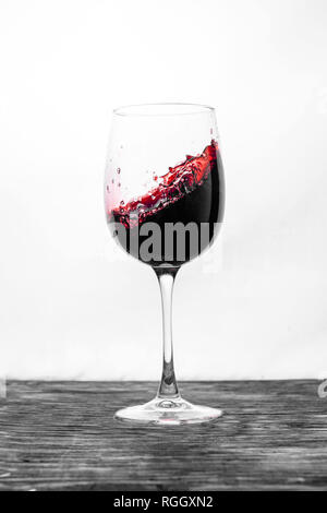 Il vino rosso in vetro schizzi in azione su uno sfondo bianco. Design elegante card Foto Stock