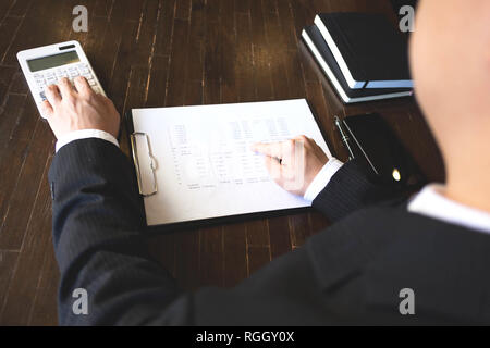 Imprenditori calcolare il reddito da attività di esportazione sul tavolo in legno.La concezione di business. Foto Stock