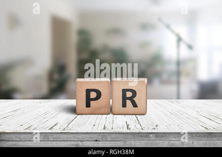 PR sign su una tabella di usura in una sala luminosa con piante verdi e un microfono Foto Stock