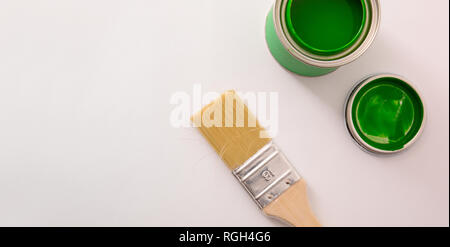 Aprire acrilico verde barattolo di vernice sul tavolo bianco e il pennello. Sfondo concettuale del materiale di verniciatura con spazio per il testo. Compositio orizzontale Foto Stock