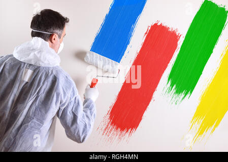Lo sfondo con il pittore professionista con tute da lavoro e il rullo sul retro di un muro bianco verniciato con quattro colori. Composizione orizzontale. Foto Stock