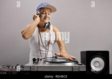 Senior dj con le cuffie la riproduzione di musica in corrispondenza di una piattaforma girevole Foto Stock