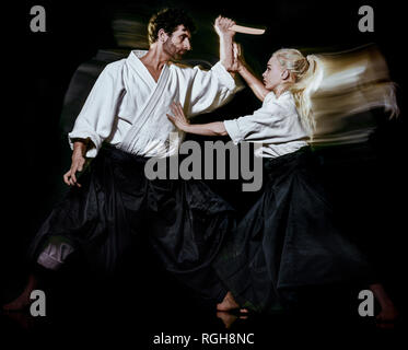 Due Combattenti budokas l uomo e la donna pratica di Aikido studio shot isolato su sfondo nero Foto Stock