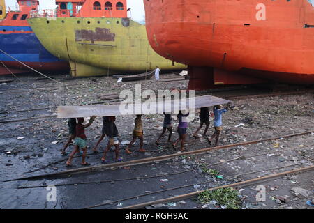 Lavoratori portano una pesante pezzo di lamiera in un cantiere navale a Dhaka, nel Bangladesh il 29 gennaio 2019. Decine di cantieri che occupa 30.96 acri del Buriganga foreshore sono state in funzione per gli ultimi cinquant'anni. Essa è principalmente utilizzata per il fissaggio e la riparazione di navi vecchie, costruire in nuove navi. Fatiche lavori in cantiere senza caschi, la maschera per il viso o scarpe di sicurezza come la loro età da 8 a 80 anni di età. © Rehman Asad / Alamy Stock Photo Foto Stock