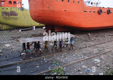 Lavoratori portano una pesante pezzo di lamiera in un cantiere navale a Dhaka, nel Bangladesh il 29 gennaio 2019. Decine di cantieri che occupa 30.96 acri del Buriganga foreshore sono state in funzione per gli ultimi cinquant'anni. Essa è principalmente utilizzata per il fissaggio e la riparazione di navi vecchie, costruire in nuove navi. Fatiche lavori in cantiere senza caschi, la maschera per il viso o scarpe di sicurezza come la loro età da 8 a 80 anni di età. © Rehman Asad / Alamy Stock Photo Foto Stock