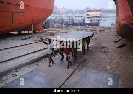 Lavoratori portano una pesante pezzo di lamiera in un cantiere navale a Dhaka, nel Bangladesh il 29 gennaio 2019. Decine di cantieri che occupa 30.96 acri del Buriganga foreshore sono state in funzione per gli ultimi cinquant'anni. Essa è principalmente utilizzata per il fissaggio e la riparazione di navi vecchie, costruire in nuove navi. Fatiche lavori in cantiere senza caschi, la maschera per il viso o scarpe di sicurezza come la loro età da 8 a 80 anni di età. © Rehman Asad / Alamy Stock Photo Foto Stock