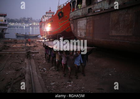 Lavoratori portano una pesante pezzo di lamiera in un cantiere navale a Dhaka, nel Bangladesh il 29 gennaio 2019. Decine di cantieri che occupa 30.96 acri del Buriganga foreshore sono state in funzione per gli ultimi cinquant'anni. Essa è principalmente utilizzata per il fissaggio e la riparazione di navi vecchie, costruire in nuove navi. Fatiche lavori in cantiere senza caschi, la maschera per il viso o scarpe di sicurezza come la loro età da 8 a 80 anni di età. © Rehman Asad / Alamy Stock Photo Foto Stock