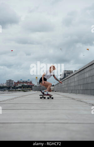 Giovane donna cavallo carver skateboard su un lungomare Foto Stock
