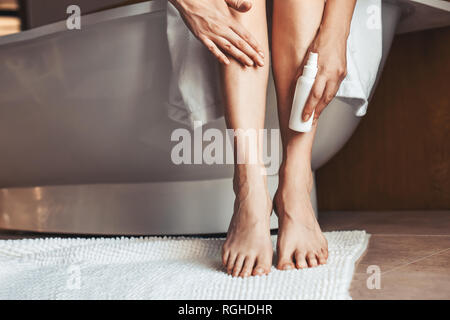 Gambe femmina. Giovane donna in bagno, accarezzare le sue gambe. Foto Stock