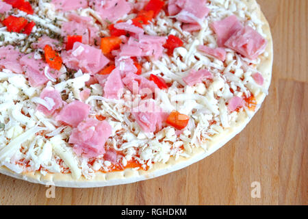 Parte del preparato gustosa pizza con pancetta e formaggio e verdure sulla piastra rotonda sulla sabbia di legno marrone tavolo da cucina vista dall'alto di close-up Foto Stock