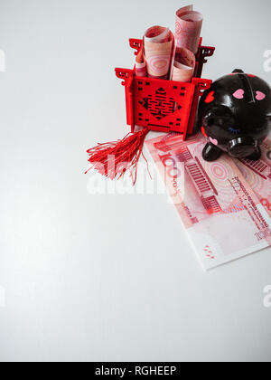 Nero salvadanaio e il Padiglione Cinese riempito di banconote, in piedi sul cinese 100 renminbi note contro uno sfondo bianco. Foto Stock