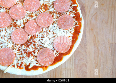 Ancora in vita con parte di (nella quasi totalità) impreparati pizza con salsiccia di sabbia sul legno bruno tavolo da cucina vista superiore closeup Foto Stock