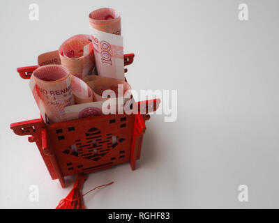 Miniatura padiglione Cinese in rosso brillante riempito con il cinese 100 renminbi banconote contro uno sfondo bianco Foto Stock