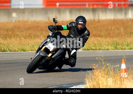 Un uomo appoggiato sopra la sua moto in una curva su di un circuito Foto Stock