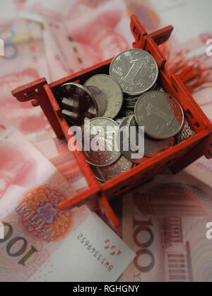 Miniatura padiglione Cinese in rosso brillante e riempito con il cinese 1 yuan monete, in piedi sul cinese 100 RMB banconote Foto Stock