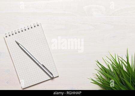 Aprire il blocco note vuote con spirale e penna grigio bianco su sfondo di legno. Vista dall'alto. Spazio di copia Foto Stock