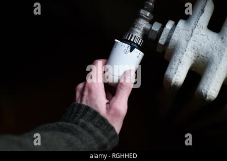 Dettaglio con una mano il controllo del calore proveniente da una famiglia radiatore Foto Stock