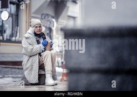 Triste infelice donna seduta sulla pietra Foto Stock