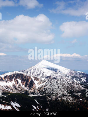 Vista delle colline pietrose con la neve e il blu del cielo. Molla di drammatica scena. Fotografia di paesaggi Foto Stock