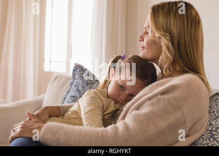 Vista laterale della madre amorevole abbracciando la sua figlia ricalcato in armi a casa Foto Stock