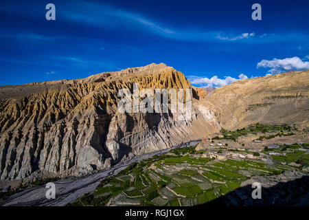 Panoramica vista aerea sulle case e il settore agricolo nei dintorni del villaggio con verdi campi di orzo, colorato ripide pareti rocciose in dista Foto Stock