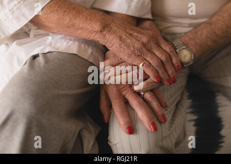 Metà vista in sezione della coppia senior tenendo le mani in camera da letto a casa Foto Stock