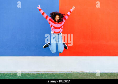 Felice giovane donna salta in aria Foto Stock
