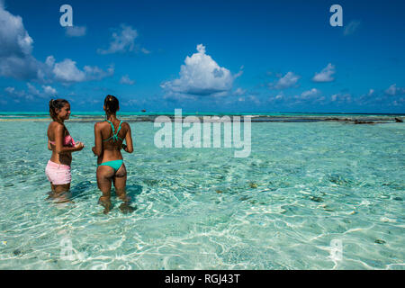 Caraibi, Colombia, San Andres, El Acuario, due donne in piedi in poco profonde acque turchesi Foto Stock