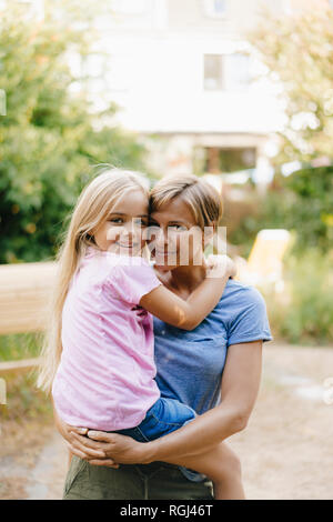 Ritratto di Madre sorridente portando la figlia in giardino Foto Stock