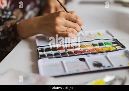 Illustrator pittura alla scrivania in un atelier, close-up Foto Stock