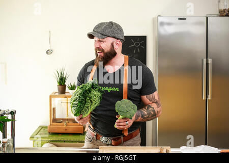 Uomo vegano scegliendo le verdure nella sua cucina Foto Stock