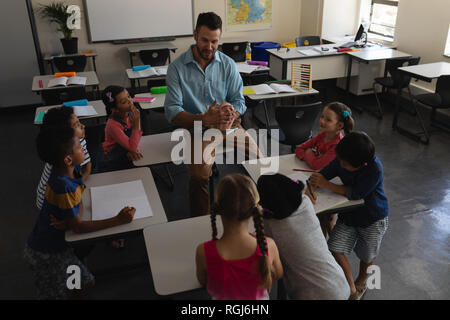 Angolo di Alta Vista del maestro maschio studiare in aula della scuola elementare Foto Stock