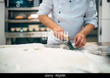 Baker lavora con impasto in forno Foto Stock