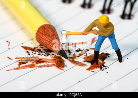 Diorama concettuale immagine di una miniatura figura affilatura di una matita su una nota prenota Foto Stock