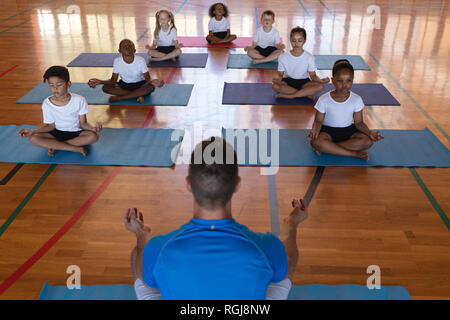 Angolo di alta vista di insegnante di yoga yoga di insegnamento a scuola i bambini a scuola ginnasta Foto Stock