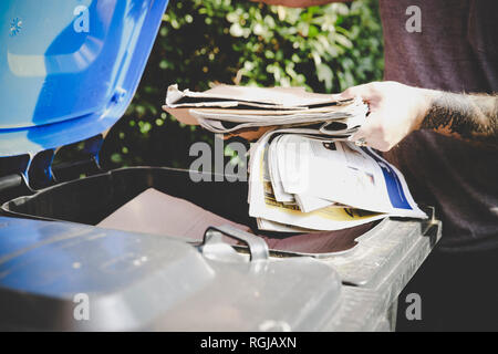 Tatuato uomo di riciclaggio dei rifiuti di carta carta in banca, vista parziale Foto Stock