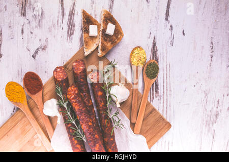 Salsiccia affumicata su una tavola di legno tavolo rustico con aggiunta di rosmarino fresco e spezie, prodotto naturale da agricoltura biologica, prodotta con metodi tradizionali Foto Stock