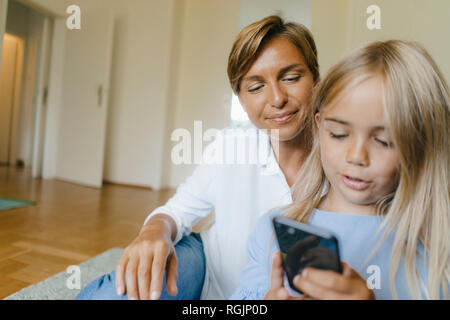 Madre e figlia guardando insieme allo smartphone Foto Stock